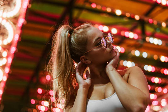 Woman wearing sunglasses with colorful lights in the background